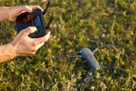 Man holds a drone remote controller in his hands. Quadcopter is on the ground ready to go and fly...