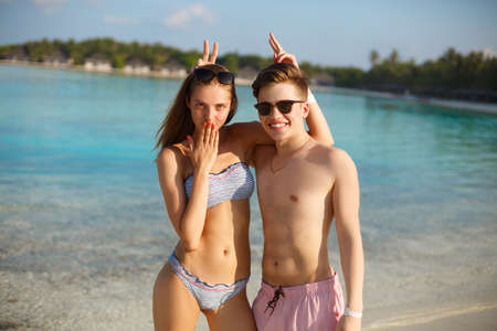Happy young couple have fun and relax on the beach. Man and woman posing for photo and fool around....