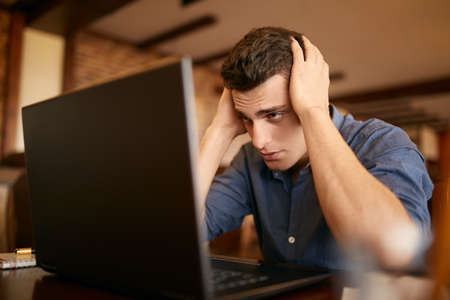 Feeling tired. Frustrated young handsome man looking exhausted and sick while sitting at his working...