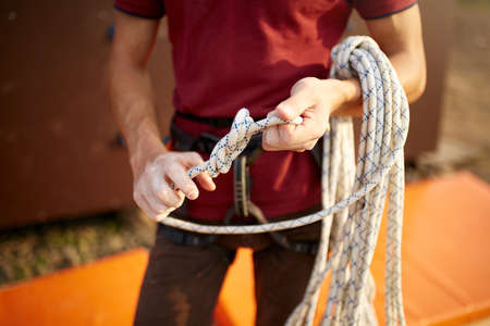 A rock climber tie a knot on a rope. A person is preparing for the ascent. Man learns to tie a knot...