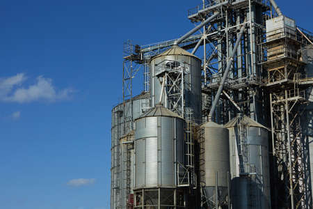 Modern grain terminal. Metal tanks of elevator. Grain-drying complex construction. Commercial grain...