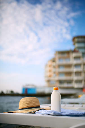 Suntan cream bottle on beach towel with sea shore on background. Sunscreen on deck chair outdoors on...