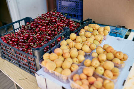 Sweet cherry and apricot on a farm market in the city. Fruits and vegetables at a farmers market. Cherries in boxes and traysの写真素材