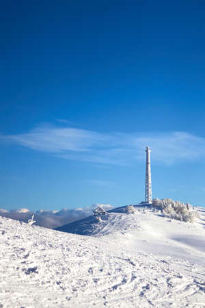 Icy cellular base station antenna covered with snow. Cell site tower on moutain hill. Telephone...