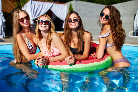 Beautiful hot pretty girls in bikini are swimming in a pool on an inflatable watermelonswim ring...