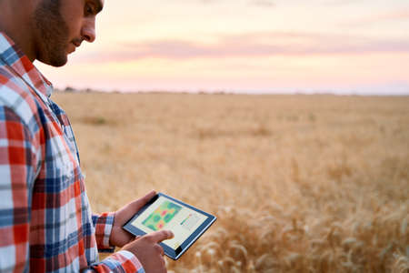 Farmer hands hold tablet using online data management software, differential fertilizer application...