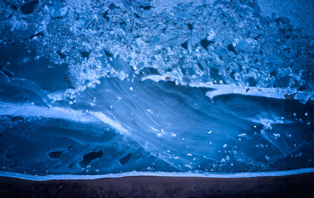 Aerial top view from above of frozen sea glaciers at the beach. Cracked ice floes in ocean on...