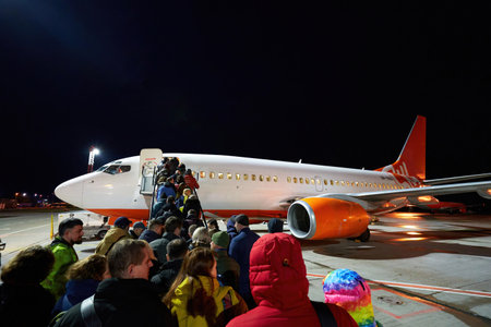 February 3, 2020. Kyiv, Ukraine. People boarding on an airplane at night in modern international airport. Passengers with luggage go up stairs to an aircraft cabin. Travel and tourism concept.のeditorial素材