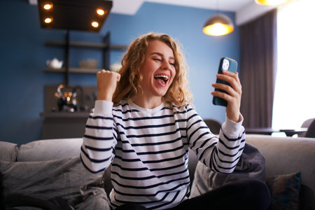 Female rejoice, celebrate a prize, big lottery win, auction victory, profitable bet on crypto stock market. Woman checks e-mail, news about success on smartphone or cellphone.の写真素材