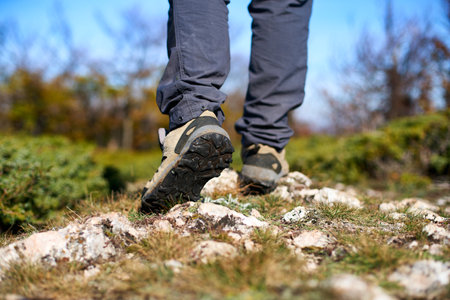 Legs of a hiker in trekking boots walking in the mountains closeup shot. Feet of walking tourist...