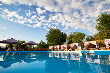 Swimming pool area with gazebos, deck chairs and sun umbrellas along the poolside in luxury resort....