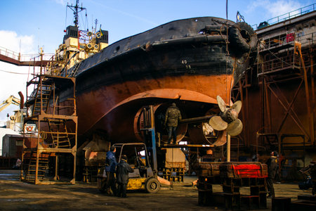 Industrial ship repair and maintenance executed by skilled workers at dry dock. Marine vessel overhaul featuring large propellers, symbolizing naval engineering, trade, and transport infrastructure.の写真素材
