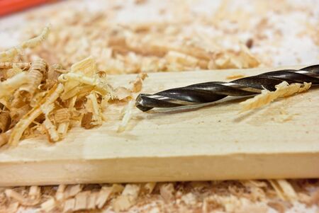 Drill lying on a wooden plank among sawdustの写真素材