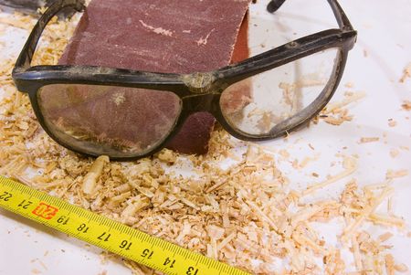 safety glasses with measure tape over white backgroundの写真素材