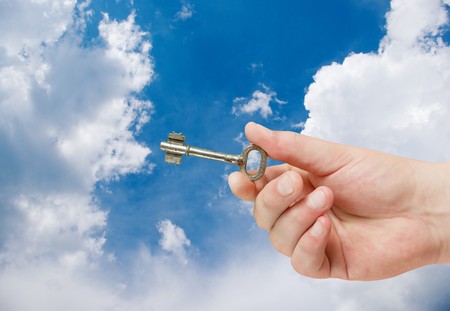 retro key in hand on blue sky backgroundの写真素材