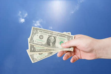 american dollar in hand on blue sky backgroundの写真素材