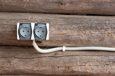 Electrical wall outlet on wood background in rural log houseの写真素材