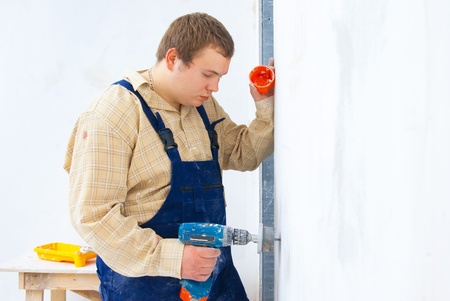 Young man drill a wall for installing power socket. homes work themeの写真素材