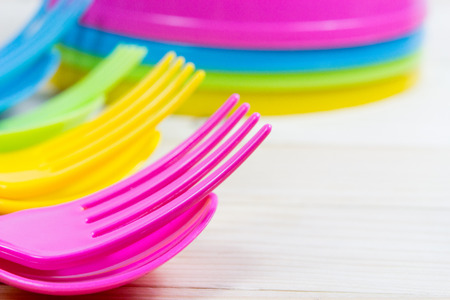 Colorful sets of cutlery and bowl plastic are arranged on wooden table backgroundの写真素材