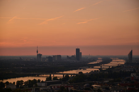 Flawless horizontal panorama of Vienna at dawn. Pink sky reflects in the Danube, skyscrapers emerge...