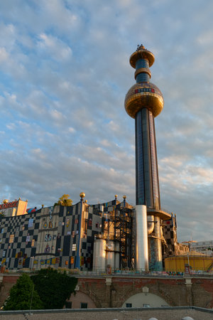 A wide view of Vienna's Spittelau plant shows the colorful facade, golden dome, and tower with sphere, blending eco architecture and artistic design in the cityscape.の写真素材