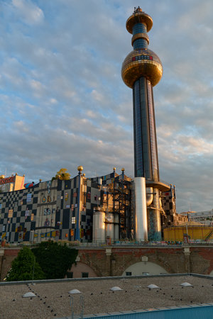 Vertical shot of Vienna's Spittelau plant showing the colorful facade, golden dome, and tower. Highlights Hundertwasser's unique architectural style and vibrant urban charm.の写真素材