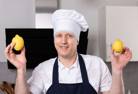Surprised smiling male cook or baker holds lemons in his hands