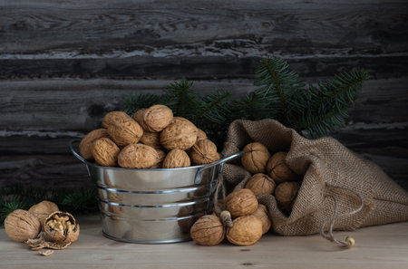 walnuts in a bowl and a sack on wooden table and a spruce branchの写真素材