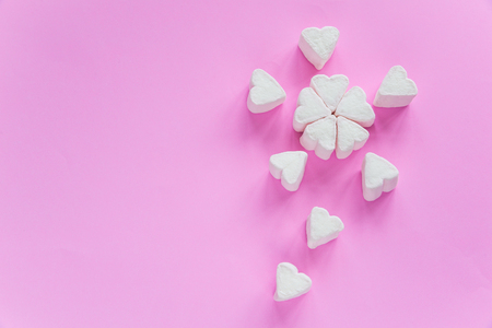 Marshmallows in heart shapes for Valentines day over pink paper background grouped like sakura flower bouquet to celebrate sweet love candy for couplesの写真素材
