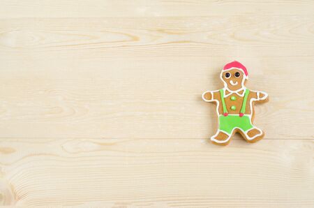 Happy gingerbread man decorated with red, green and white color icing on wooden background with copy space for cooking, christmas party, new year's day, new year's eve, silvester, and winter holidayの写真素材