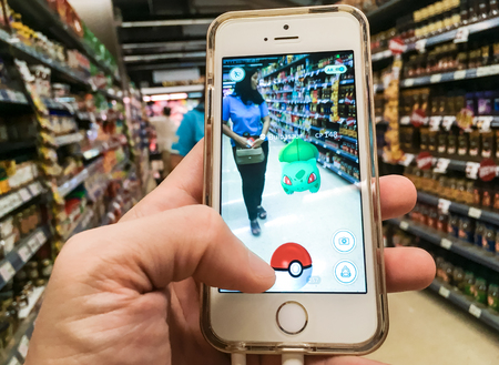 BANGKOK, Thailand - August 7, 2016: An iPhone user playing Pokemon Go game in supermarket of...