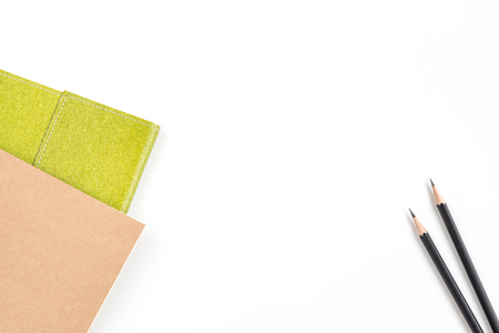 Recycled notebook in green and brown color and two black pencils over white background with copy space for text insertion or decorationの写真素材