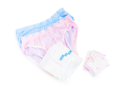 Sanitary napkin and pads in stacks and piles with women's underwear (lingeries) in pink and blue colour over white background with copy spaceの写真素材