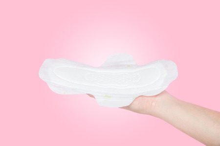 White, new, clean, thin, and slim sanitary napkin pad on female or woman hand for menstrual period day use on every month isolated on light pink background (clipping path included),health care conceptの写真素材