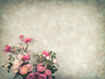 Vintage old wall background with grain texture decorated with pink flowers and roses in antique vase with copy space for text decoration and insertionの写真素材