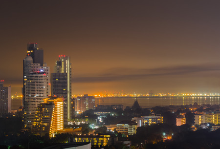Night cityscape of skyline, tall buildings and cities near sea or river with gold and dark sky for copy spaceの写真素材