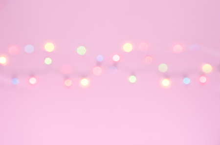 Blurry or bokeh Xmas lights on pink colour background with copy space for text,  wording insertion, Christmas ornament for tree or house holiday concept on new yearの写真素材
