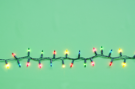 Xmas light bulbs on string in multi colours; blue, yellow, green, pink & red on green background with copy space for Christmas text decor, new year or special event celebration (pine tree ornament concept)の写真素材