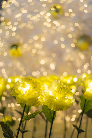 Led lights of yellow marigold fabric handmade flower garden decorated with blur light bokeh of Xmas tree for celebrating Christmas season and new yearの写真素材