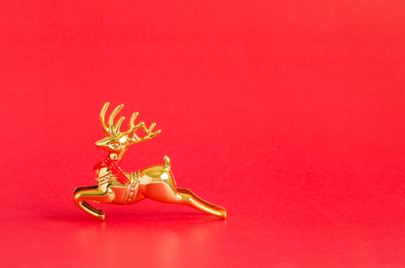 Gold reindeer over vivid red Christmas background with copy space for text, logo or product insertion, happy new year and holiday season conceptの写真素材