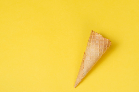 Ice cream waffle cone over yellow background with copy space for text, logo or wordings insertion or decoration, summer cold sweet snackの写真素材