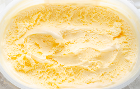 Ice cream of vanilla flavour texture pattern background in white plastic bowl or box with ice cubes surrounding, summer sweet conceptの写真素材