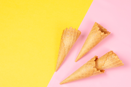 Ice cream waffle cones over bright yellow and sweet pink background with copy space for text, logo or wordings insertion or decoration, summer cold sweet snackの写真素材