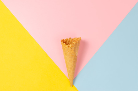 Ice cream waffle cone over light yellow, sweet pink and light blue background with copy space for text, logo or wordings insertion or decoration, colourful summer cold sweet snack conceptの写真素材