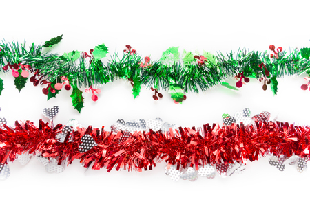 Green red mistletoe tinsels on white background, Christmas decorative ornament for special holiday celebrationの写真素材