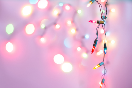 Christmas light bulbs turned on or lid on string in colours with sweet love purple & pink background, sweet holiday concept for Xmas party, special love celebration or happy new year (selective focus)の写真素材