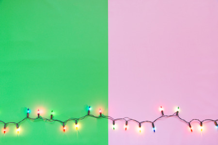 Christmas light bulbs were turned on or lid on string in colours; blue, yellow, red, pink, orange and green over pink & green background, holiday concept for Xmas or special occasion celebrationの写真素材
