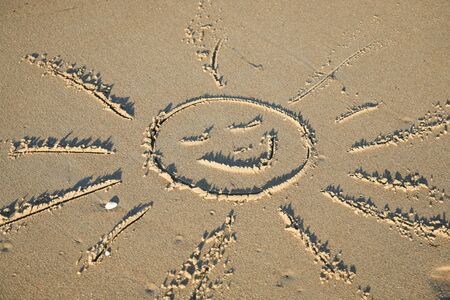 Sun drawn in the sand of a beachの写真素材