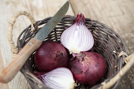 Red onions in a basket with knifeの写真素材