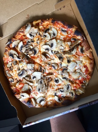 Pizza with mushrooms and tomato sauce in a paper boxの素材